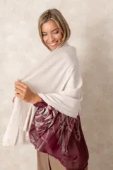 Pashmina de tejido suave con diseño asimétrico, cierre lateral con botón y acabado liso en color bordó.