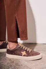 Pantalón de jean color marrón, de corte recto y tiro medio, con cierre frontal con botones.