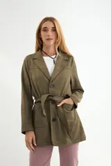 Chaqueta de gamuza sintética color verde militar, con solapas, cierre frontal de botones y cinturón ajustable del mismo tejido. Presenta bolsillos frontales tipo parche.