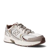 Championes urbanos New Balance modelo 530, en color beige y marrón con base blanca, confeccionados en malla transpirable y superposiciones sintéticas, con el característico logo 'N' en los laterales.