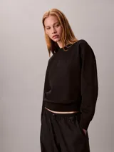 Buzo de felpa Calvin Klein de color negro, corte regular y cuello redondo, con el nuevo emblema con logo texturizado en el pecho y puños, cuello y bajo de canalé.
