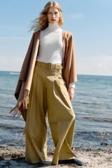Jersey de punto liso en color beige, con cuello alto y manga larga con detalle de botones metálicos en los puños.