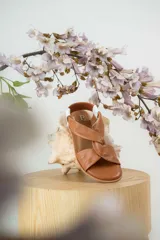 Sandalias chatitas de cuero en tono nude, con diseño de tiras cruzadas en el empeine y elástico en el talón para mayor ajuste. Presentan una plantilla acolchada y detalles en cuero charolado en la parte posterior.