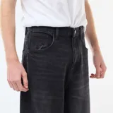 Pantalón de jean estilo baggy, de corte holgado y tiro medio, en color negro con efecto lavado. Cuenta con diseño de cinco bolsillos y cierre frontal con botón y cremallera.