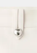 Pantalón sastrero de tiro bajo y diseño largo con botamanga acampanada, color blanco, con trabillas y cierre oculto.