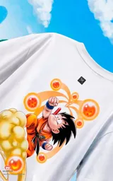 Remera blanca de corte oversize con estampa frontal de Goku sobre la nube voladora rodeado de las esferas del dragón.