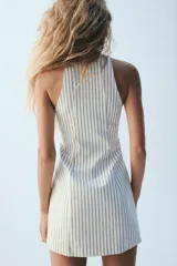Vestido mini Zara de rayas diplomáticas, con escote en pico, diseño sin mangas, doble botonadura frontal decorativa y cierre lateral con cremallera oculta.
