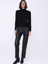 Sweater negro de cuello alto, mangas largas con botones decorativos en los puños y corte ajustado.