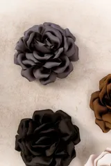 Broche prendedor con forma de flor grande, confeccionado en tela de seda color gris oscuro.
