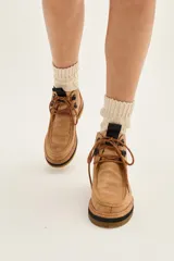 Borcego de cuero color marrón con diseño de costuras tipo mocasín en la puntera, cordones jaspeados y suela de goma con plataforma en capas.