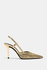 Zapato de tacón alto destalonado en color dorado con acabado metalizado y diseño de efecto trenzado. Presenta una tira trasera con elástico y puntera fina.