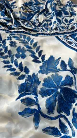 Vestido midi de tirantes finos y escote en V, color blanco con estampado botánico en azul índigo, corte ajustado en la cintura y falda fluida con volados.