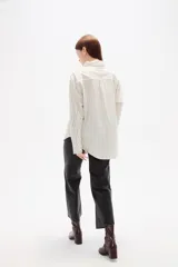 Camisa de algodón con diseño de rayas verticales finas en tonos neutros, corte holgado, cuello camisero y cierre frontal con botones.