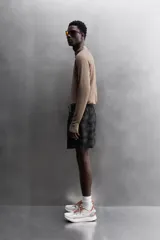 Short deportivo negro con estampado abstracto, cintura elástica ajustable con cordón, bolsillos laterales y trasero con cierre, forro interior y detalle de perforaciones en el ruedo.