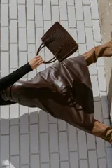 Bolso tipo mini city color marrón oscuro con textura de relieve de cocodrilo. Tiene doble asa de mano y una bandolera extraíble. Cuenta con compartimentos interiores con cremalleras metálicas.