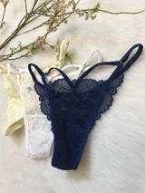 Pack de tres tangas de encaje con diseño de tiras laterales regulables. El conjunto incluye una pieza en color azul marino, una en color blanco y una en color champagne.