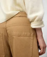 Pantalón de mujer color camel, estilo barrel fit, confeccionado en denim de algodón 100%. Presenta cierre con botón metálico, cinco bolsillos y pierna ancha con pinza bajo la rodilla.