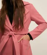 Saco largo negro confeccionado en polivelour, con solapas en el cuello, trabillas en los laterales de la cintura y cinturón franja de tejido.