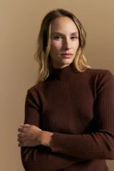 Polera de tejido acanalado con cuello alto, corte ajustado al cuerpo y mangas tres cuartos con terminaciones onduladas en los puños.