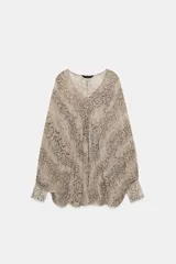Blusa de escote en V con estampado de piel de serpiente en tonos beige y marrón. Tiene mangas largas tipo murciélago con puños ajustados y cierre frontal con botones.