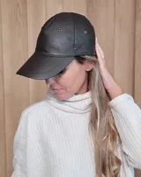 Gorro tipo visera de cuero marrón con ojalillos metálicos de ventilación.