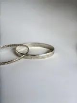 Pulsera tipo esclava rígida de diseño ancho y superficie lisa con acabado brillante.