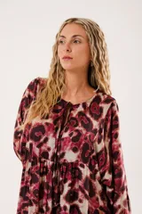 Vestido midi con estampado animal print en tonos borgoña y beige, con escote redondo y abertura en el pecho que se ajusta con lazos finos. De silueta relajada, manga larga tipo globo con terminación fruncida y falda amplia con recortes.