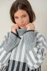Sweater tejido a rayas horizontales color beige, marrón y negro, de cuello alto y corte holgado.