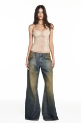 Musculosa de estilo corset confeccionada en tul beige con aplicaciones de encaje floral y cierre frontal con botones pequeños. Presenta breteles finos y un diseño semitransparente con frunces centrales.