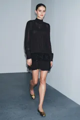 Vestido corto de viscosa color negro con cuello perkins y manga larga. Presenta un fajín de terciopelo integrado con bordados a tono y detalle de lazadas laterales.
