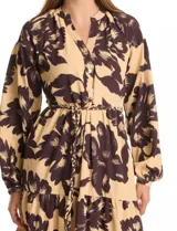 Vestido maxi de crepe estampado con flores grandes en tonos beige y marrón oscuro. Presenta escote en V con botones, mangas largas anchas con botón en los puños, y cintura con pasadores y cordón de ajuste.