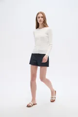 Remera de manga larga al cuerpo confeccionada en viscosa, de color blanco, con cuello a la base y cierre frontal de botones.