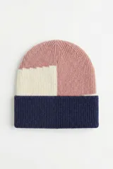 Gorro tipo beanie de punto acanalado con diseño de bloques de color en tonos rosado, crema y azul marino.