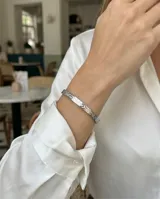 Esclava rígida de acero inoxidable con diseño de eslabones circulares grabados en toda su superficie.