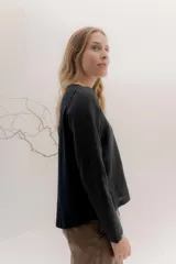 Remera de manga larga con escote a la base, color blanco, con un bordado central de dos líneas negras verticales en la parte delantera. La parte delantera es de lino y la espalda de algodón con spandex.