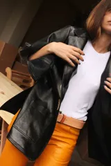 Blazer de cuero color celeste metalizado, con solapas, cierre con broches tipo tanca de madera y puños con detalle de piel sintética marrón.