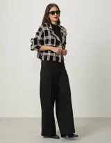 Chaqueta negra de tejido de punto con diseño a cuadros en tonos beige y blanco, cuello tipo blazer y bolsillos frontales.