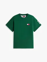 Remera verde de algodón con cuello redondo y corte amplio. Presenta el logo de Tommy Hilfiger en el pecho y un logo oversize en la parte trasera. Tiene mangas cortas con hombros caídos y un parche con logo en la manga.