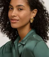 Par de caravanas doradas de metal reciclado, con diseño asimétrico de flor. Una caravana presenta una flor completa con tallo alargado, mientras que la otra tiene un solo pétalo.