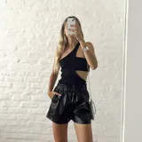 Top negro asimétrico con un solo hombro, corte en la cintura y abertura lateral.