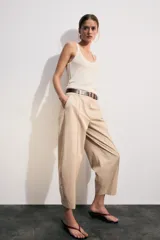 Pantalón tiro bajo color marrón, de corte globo y pernera recta con raya marcada al frente. Incluye trabillas y un cinturón marrón oscuro con hebilla metálica.