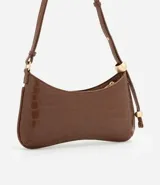 Cartera baguette marrón con textura croco, confeccionada en material sintético. Tiene cierre de cremallera y correa de hombro con esferas doradas.