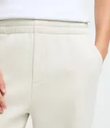 Pantalón jogger de algodón con felpa, color beige, con cintura elástica, cordón ajustable, bolsillos laterales y puños elásticos en los tobillos.