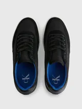 Zapatillas urbanas Calvin Klein con diseño de corte bajo. Presentan una combinación de materiales en la capellada, incluyendo paneles de nailon, cuero y ante en color negro. Destacan por su suela de goma blanca con el logo de la marca estampado en el lateral, forro interior en color azul vibrante y cierre mediante cordones.