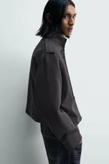 Chaqueta cropped de algodón con cuello mao y manga larga. Presenta un diseño de inspiración militar con alamares decorativos en contraste en el frente, trabillas en los hombros y cierre frontal con ganchos metálicos.