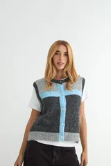 Chaleco de tejido de punto con diseño de bloques de color en gris, gris oscuro y celeste. Presenta cuello redondo, cierre frontal con botones y terminaciones acanaladas.