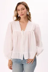 Blusa blanca de mangas largas abullonadas, con escote en V con lazo y volados.