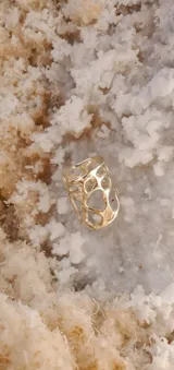 Anillo ancho de diseño orgánico y calado, con apariencia de red o magma solidificado.