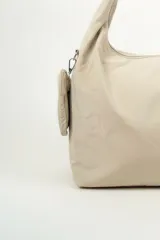 Bolso tipo shopper de nylon color beige, con cierre superior y correa de hombro integrada. Incluye un pequeño monedero colgante lateral.