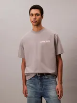 Remera gris de corte regular y mangas cortas, con cuello redondo y el logotipo de Calvin Klein bordado en color rosado en el pecho.